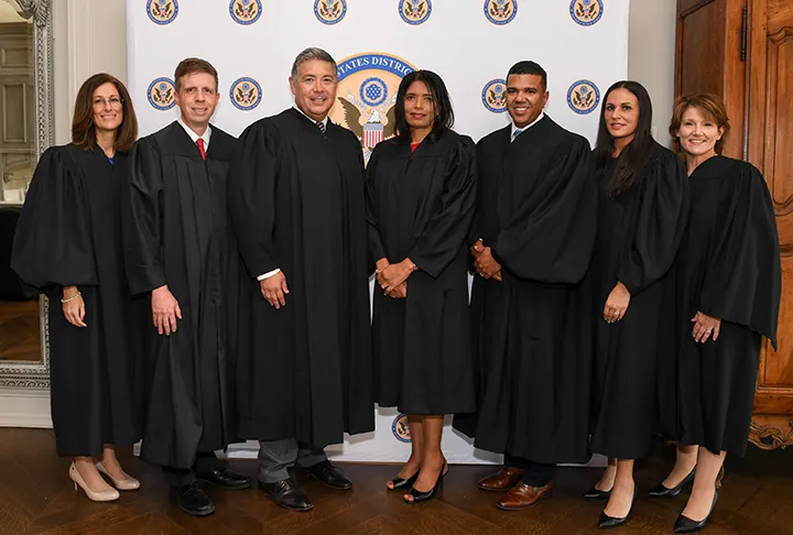 Seven magistrate judges wearing judicial robes stand together after being sworn in.